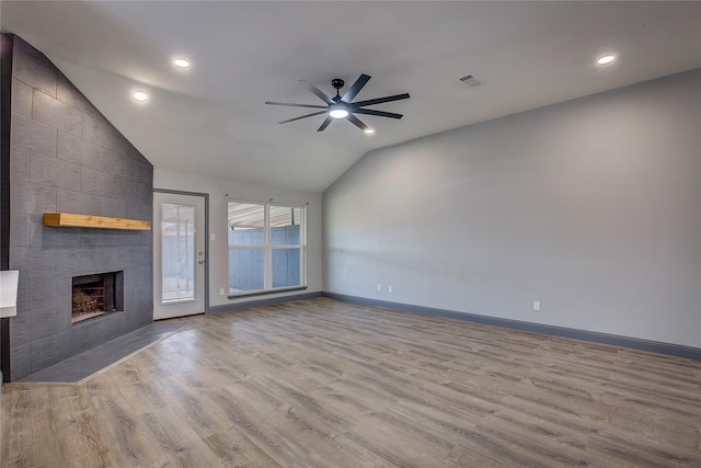 unfurnished living room with lofted ceiling, a tile fireplace, light hardwood / wood-style floors, and ceiling fan