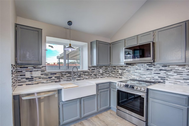 kitchen featuring vaulted ceiling, appliances with stainless steel finishes, sink, and decorative backsplash