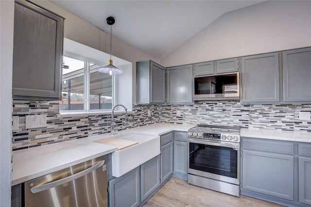 kitchen with sink, tasteful backsplash, vaulted ceiling, appliances with stainless steel finishes, and pendant lighting