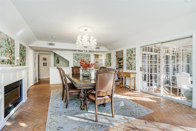 dining room featuring built in shelves, vaulted ceiling, and a notable chandelier