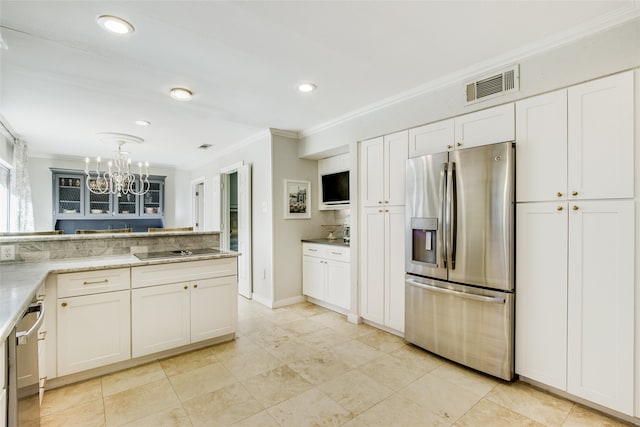 kitchen with white cabinetry, tasteful backsplash, a notable chandelier, appliances with stainless steel finishes, and ornamental molding