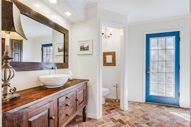 bathroom with a chandelier, vanity, toilet, and ornamental molding