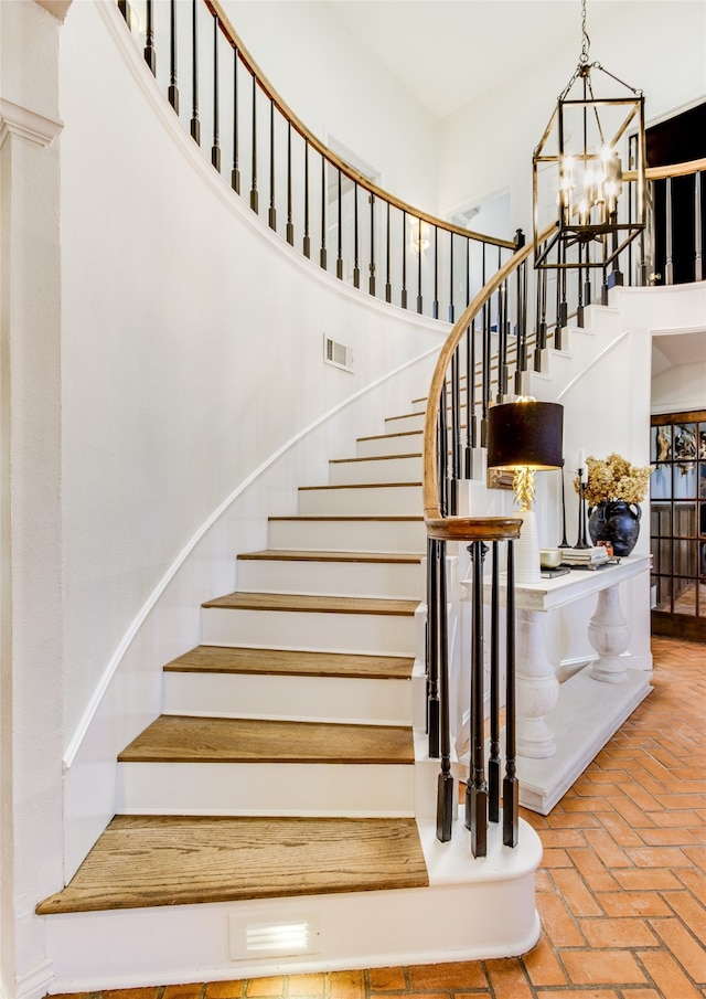 stairway with a towering ceiling and a chandelier