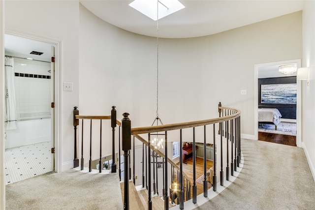 hall with carpet, a notable chandelier, and lofted ceiling with skylight