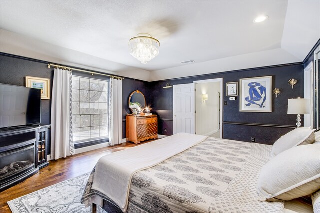 bedroom with a notable chandelier and dark wood-type flooring