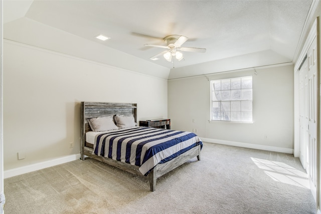 carpeted bedroom with a raised ceiling, ceiling fan, a closet, and vaulted ceiling