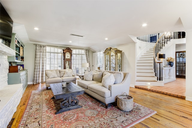 living room featuring light hardwood / wood-style floors, lofted ceiling, and ornamental molding