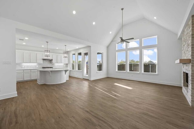 unfurnished living room with dark hardwood / wood-style flooring, plenty of natural light, high vaulted ceiling, and a fireplace