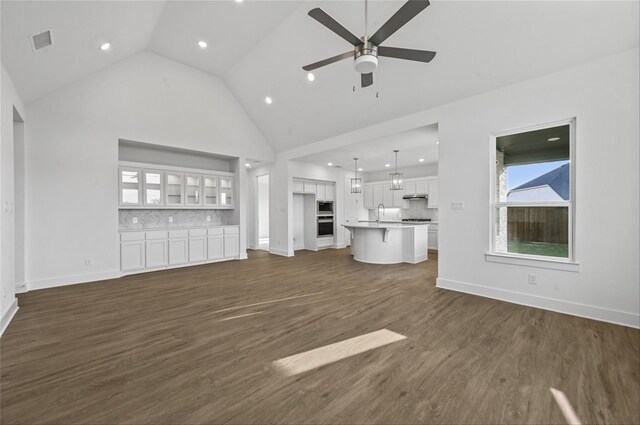 unfurnished living room with ceiling fan, high vaulted ceiling, sink, and dark hardwood / wood-style flooring