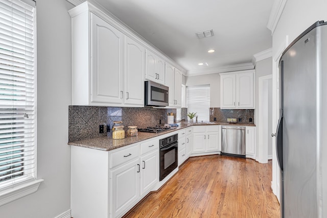 kitchen featuring appliances with stainless steel finishes, white cabinetry, dark stone counters, and sink