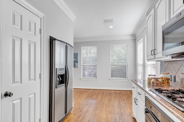 kitchen featuring white cabinetry, crown molding, appliances with stainless steel finishes, and tasteful backsplash