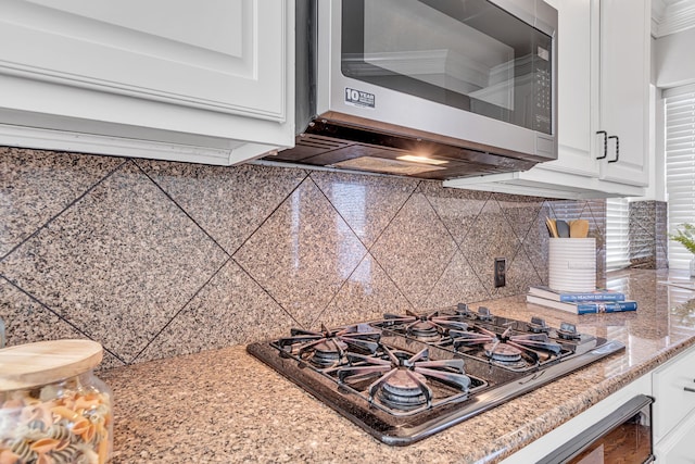 room details featuring decorative backsplash, crown molding, white cabinets, and gas stovetop