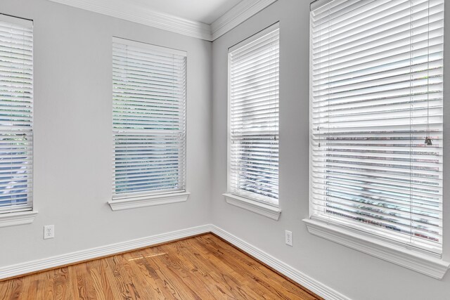 empty room featuring crown molding and hardwood / wood-style flooring