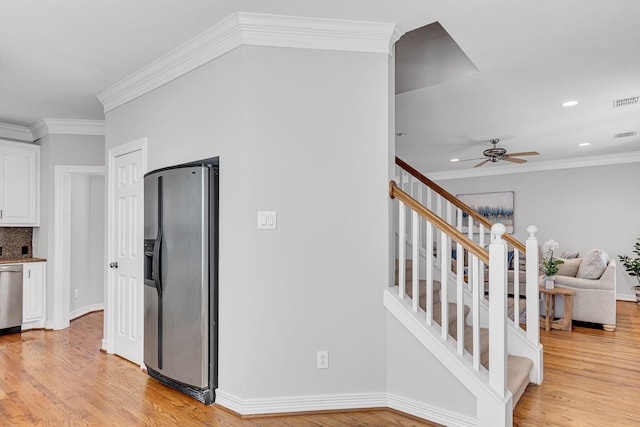 staircase with hardwood / wood-style floors, ceiling fan, and crown molding