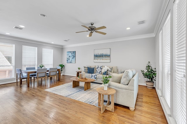 living room featuring ceiling fan, ornamental molding, and light wood-type flooring