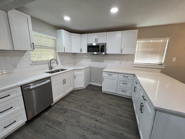 kitchen with sink, decorative backsplash, appliances with stainless steel finishes, dark hardwood / wood-style flooring, and white cabinetry