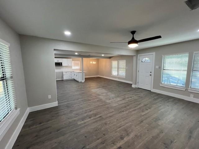 unfurnished living room featuring a wealth of natural light, dark hardwood / wood-style floors, and ceiling fan