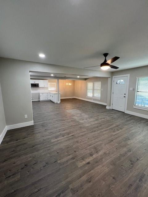 unfurnished living room with dark hardwood / wood-style flooring and ceiling fan