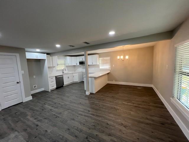 kitchen featuring decorative backsplash, dark wood-type flooring, dishwasher, white cabinetry, and hanging light fixtures