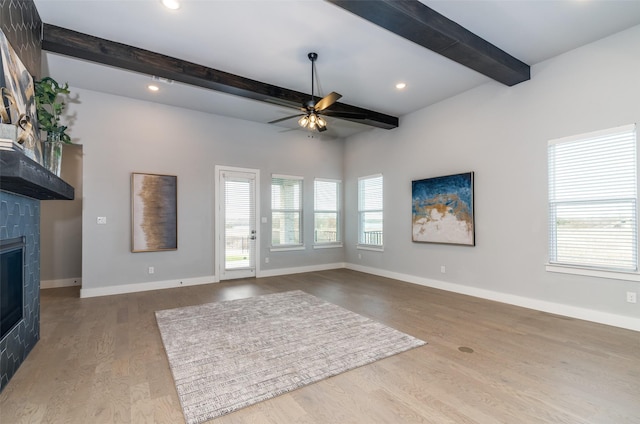 unfurnished living room featuring hardwood / wood-style floors, ceiling fan, a healthy amount of sunlight, and a tiled fireplace