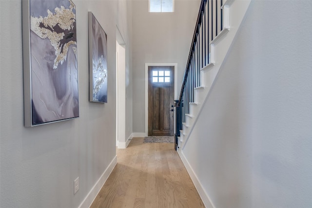 entrance foyer featuring light wood-type flooring and a towering ceiling