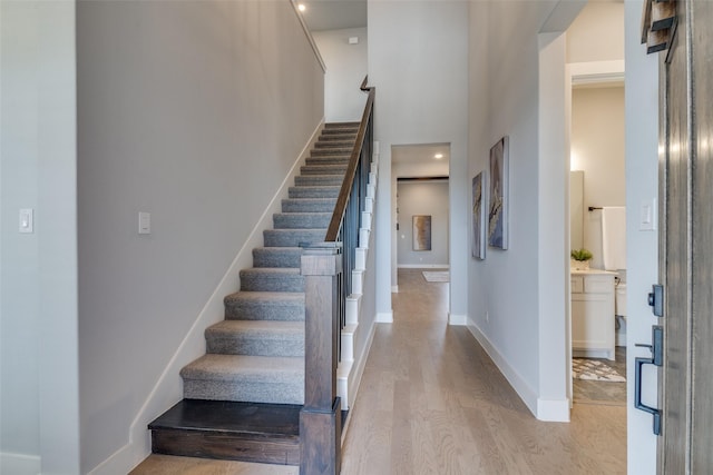 stairs featuring wood-type flooring and a towering ceiling