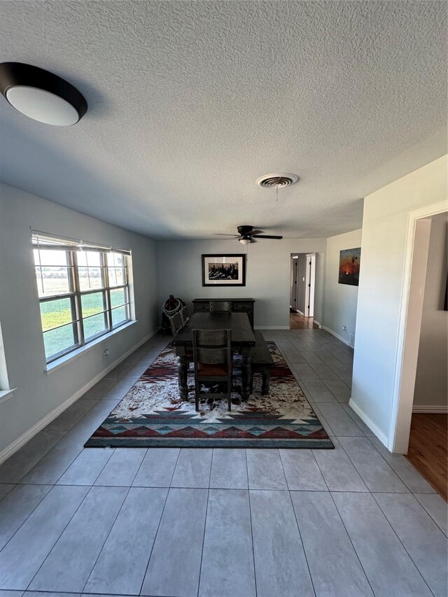 dining space with tile patterned flooring, ceiling fan, and a textured ceiling