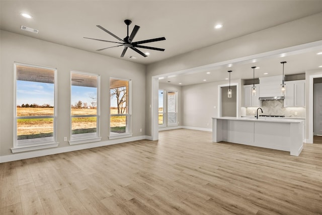 unfurnished living room featuring ceiling fan and light hardwood / wood-style flooring