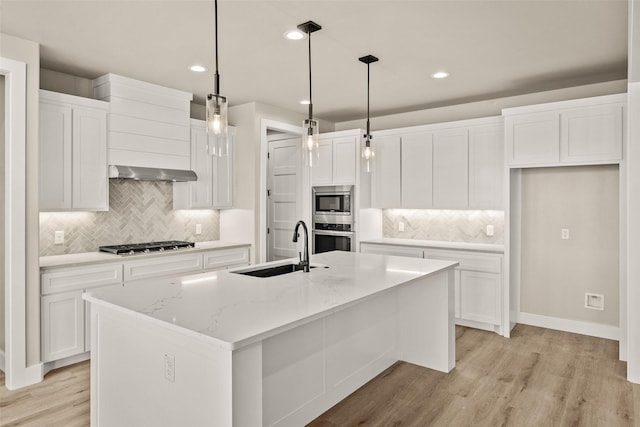 kitchen with sink, white cabinetry, a kitchen island with sink, and hanging light fixtures