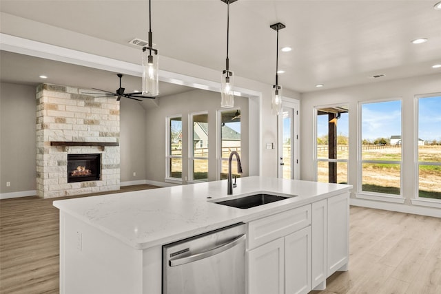 kitchen featuring white cabinetry, sink, stainless steel dishwasher, an island with sink, and decorative light fixtures