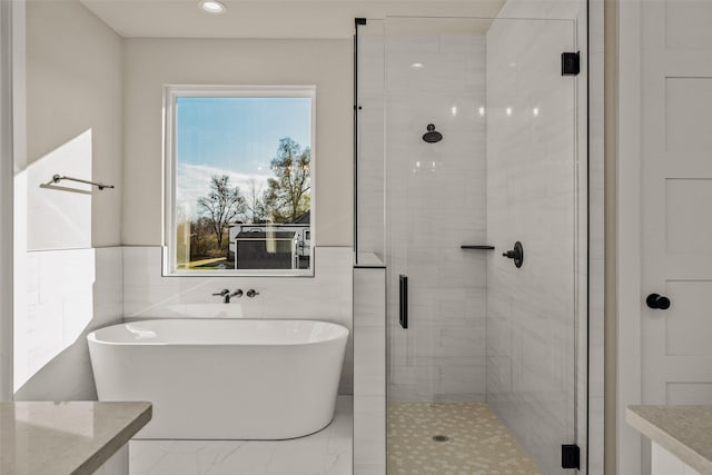 bathroom featuring shower with separate bathtub and tile walls