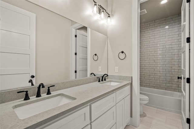 full bathroom with tile patterned floors, tiled shower / bath, vanity, and toilet