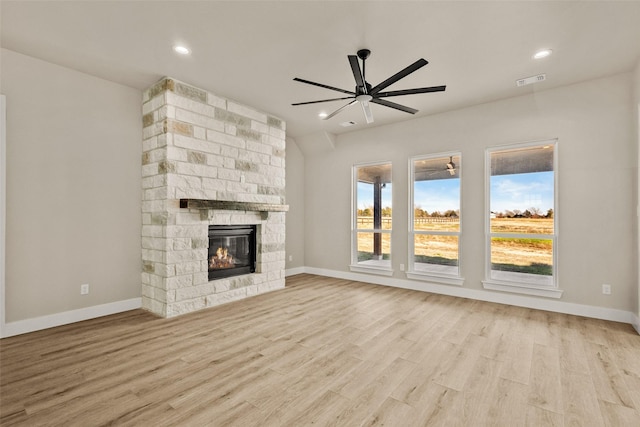 unfurnished living room featuring a stone fireplace, ceiling fan, and light wood-type flooring