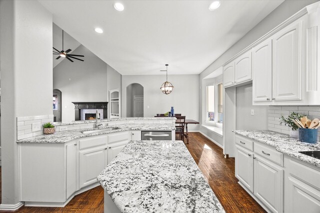 kitchen with kitchen peninsula, hanging light fixtures, ceiling fan, decorative backsplash, and white cabinetry