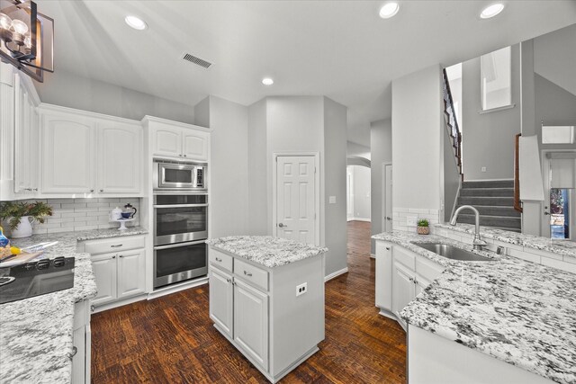 kitchen featuring light stone countertops, white cabinetry, a kitchen island, and sink