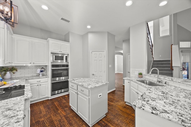 kitchen with light stone countertops, sink, a kitchen island, and white cabinets