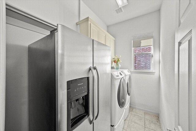 laundry area with light tile patterned flooring, cabinets, and washing machine and clothes dryer