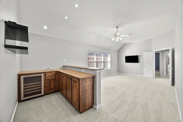 kitchen with light colored carpet, lofted ceiling, kitchen peninsula, and wine cooler