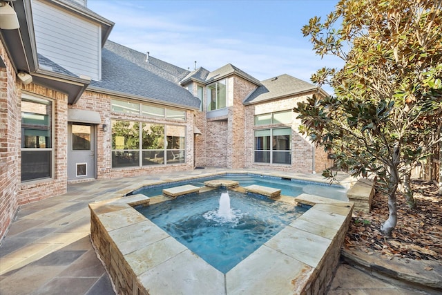 view of pool with an in ground hot tub, a patio, and pool water feature