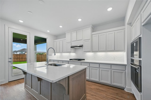 2341 Flora Dr, Mclendon Chisholm, TX 75032 - kitchen with stainless steel appliances, under cabinet range hood, a kitchen island with sink, light countertops, and dark wood-style floors