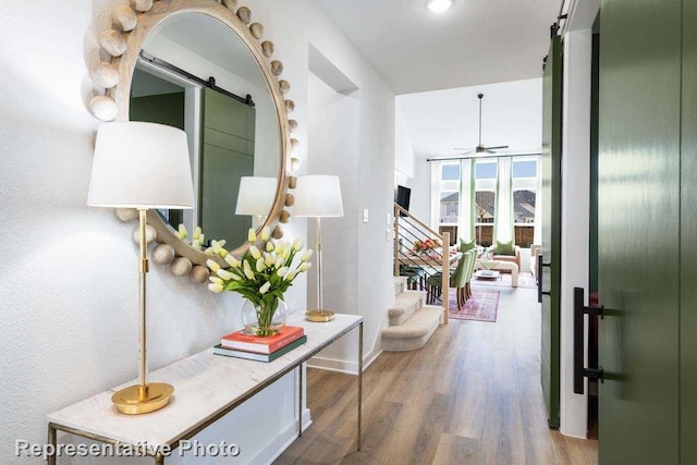 corridor featuring hardwood / wood-style flooring, a barn door, and expansive windows