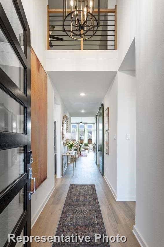 foyer entrance with wood-type flooring, a towering ceiling, and a chandelier