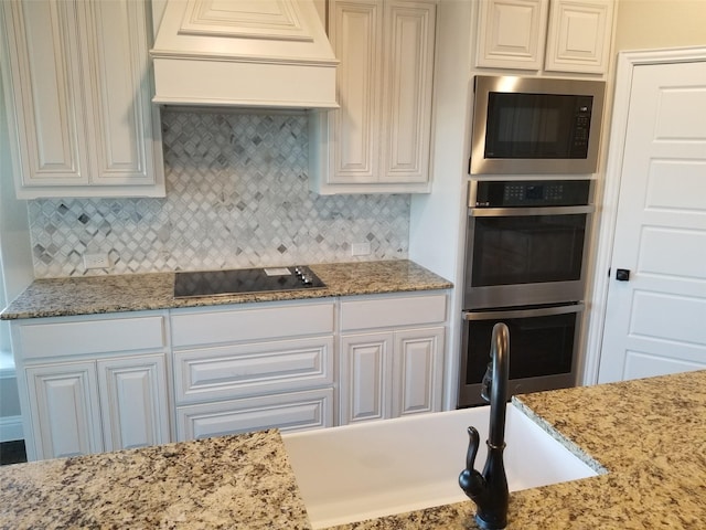 kitchen with backsplash, custom exhaust hood, stainless steel double oven, black electric cooktop, and built in microwave