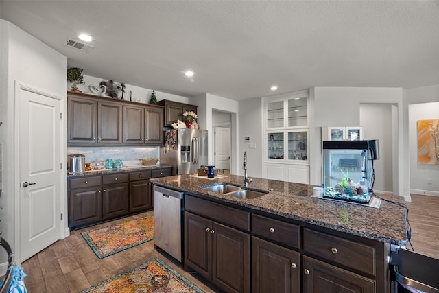 kitchen featuring sink, light hardwood / wood-style flooring, decorative backsplash, dark brown cabinets, and stainless steel appliances