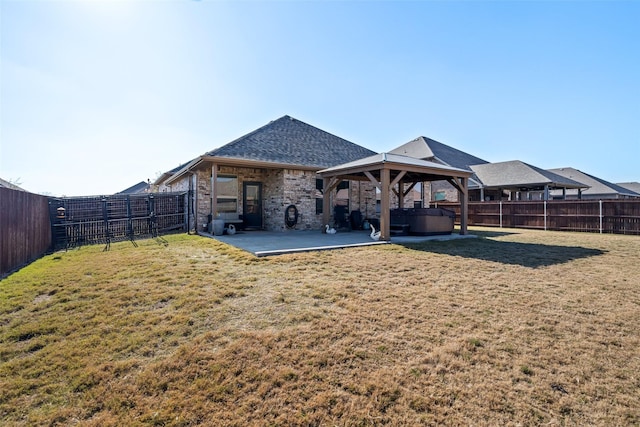 back of property with a lawn, a patio area, and a hot tub