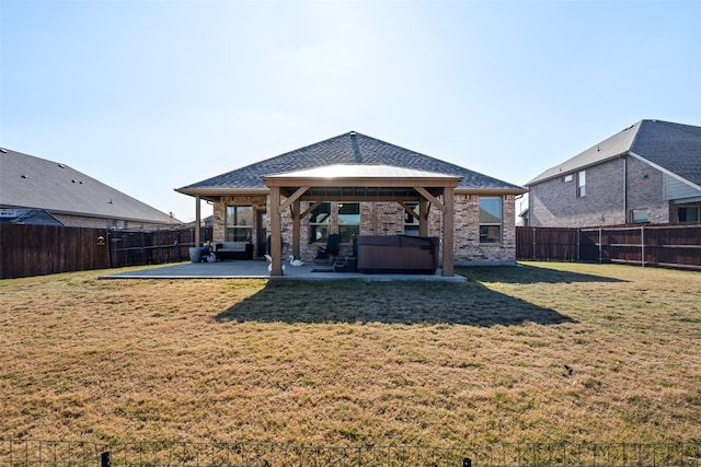 back of property with a patio area, a yard, and a hot tub