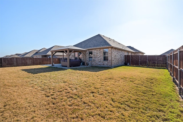 back of house featuring a gazebo, a hot tub, and a lawn