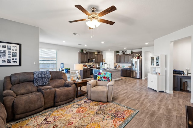 living room featuring ceiling fan, light hardwood / wood-style flooring, and sink