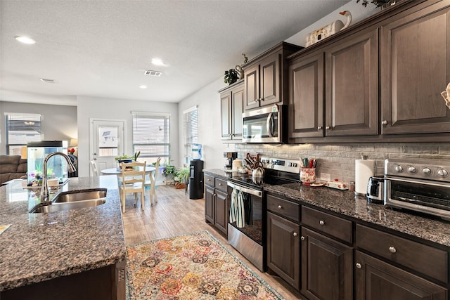 kitchen with appliances with stainless steel finishes, tasteful backsplash, dark brown cabinets, and sink