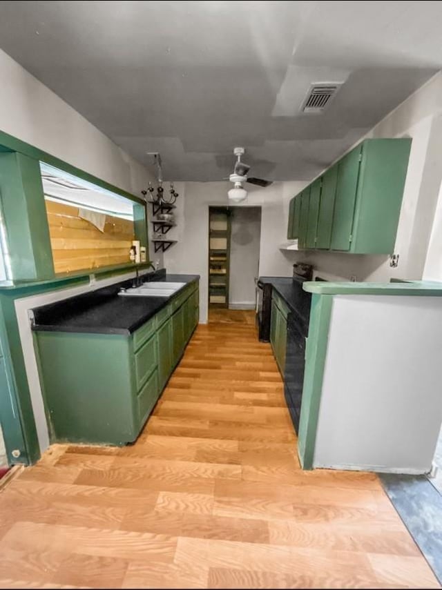 kitchen featuring ceiling fan, green cabinets, light wood-type flooring, and sink